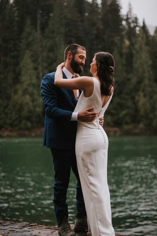 Bride and groom holding hands beside the lake at their PNW cabin elopement