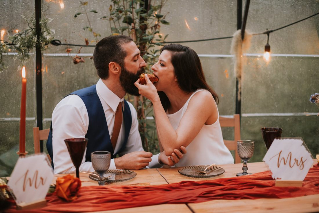 Bride and groom laughing together inside the greenhouse by the creek