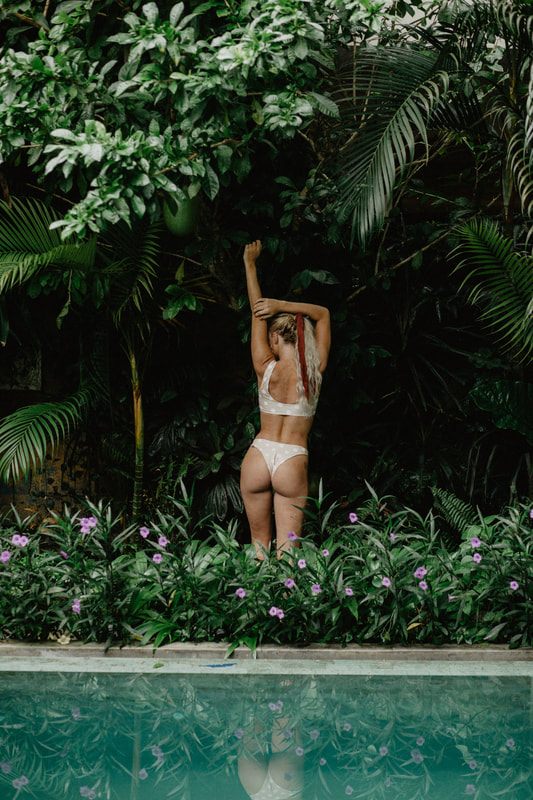 Lindsey O. modeling Cheeky Swim swimwear, posing near the waterline, in Bali, Indonesia.