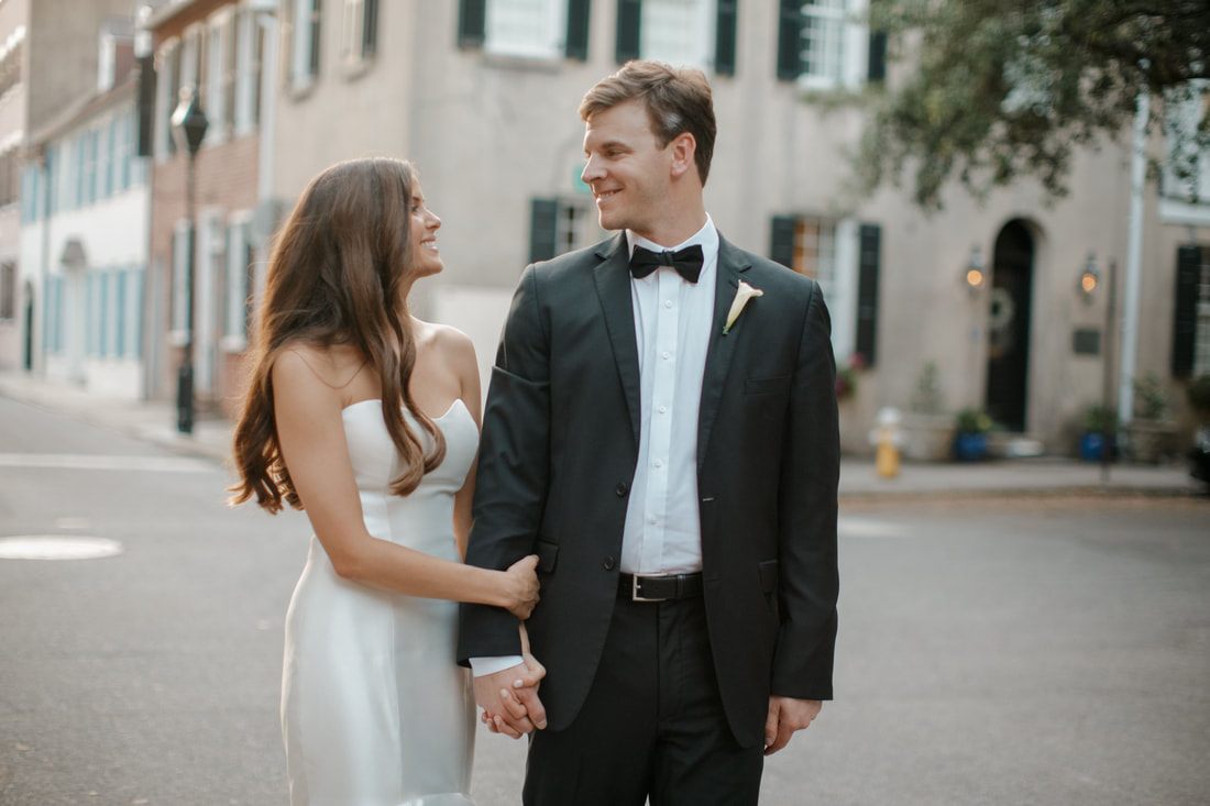 Tyler and Emily embracing in front of a Charleston row house