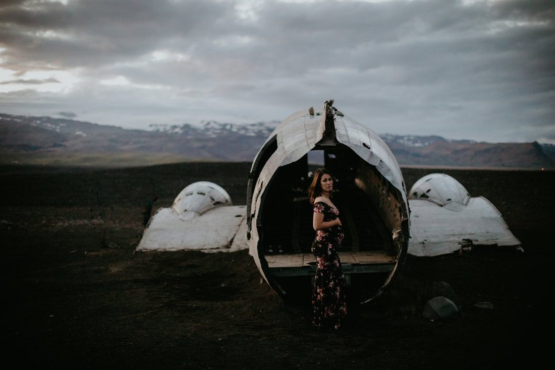 Pregnant woman standing before Iceland's Solheimasandur plane wreck at night
