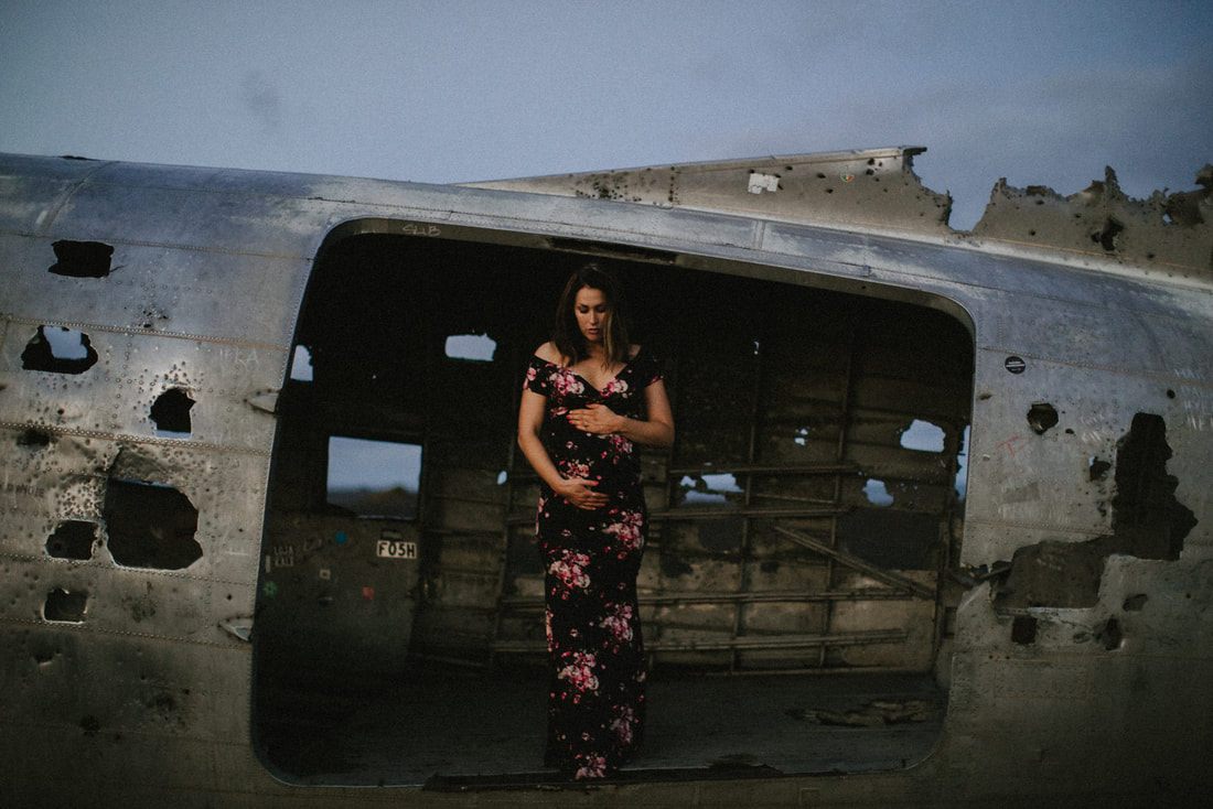 Close-up maternity portrait lit by flash against the wrecked plane