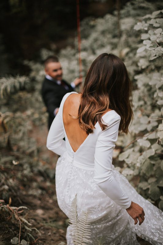 The couple walking back toward the cabin through tall evergreen trees