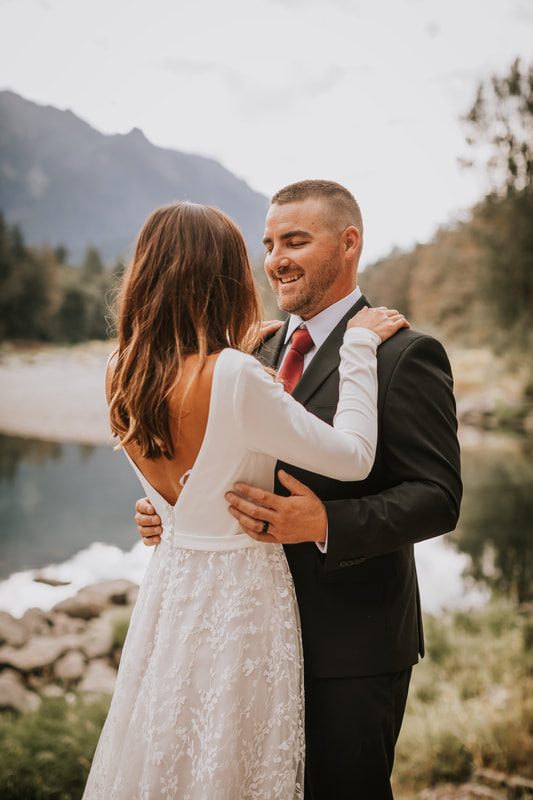 The couple laughing as they feed each other a bite of cake