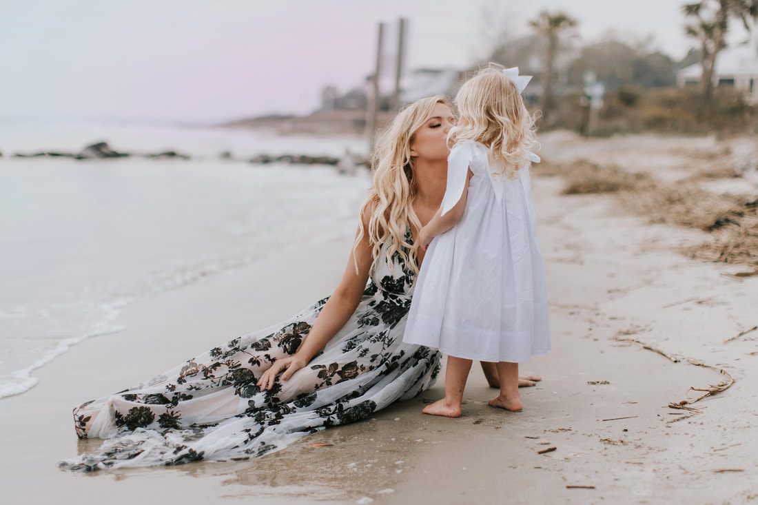 Mother and daughter embracing on the quiet winter beach at sunset