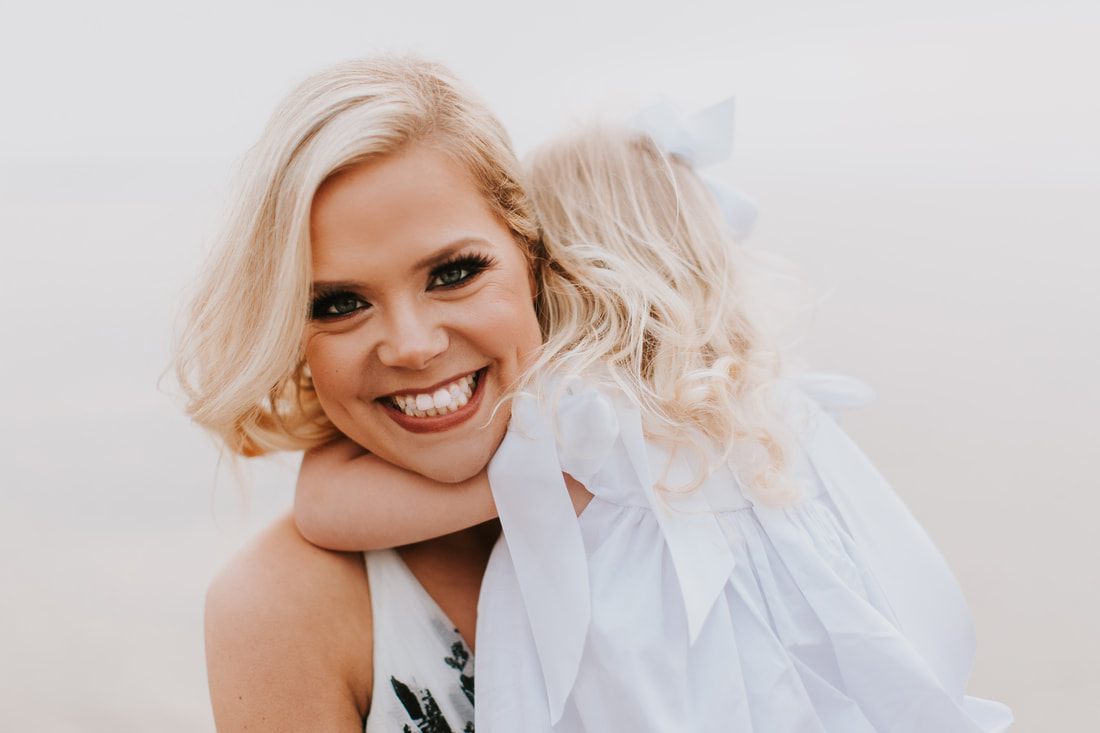 Close-up portrait of Liz and Aubrey smiling together at the beach