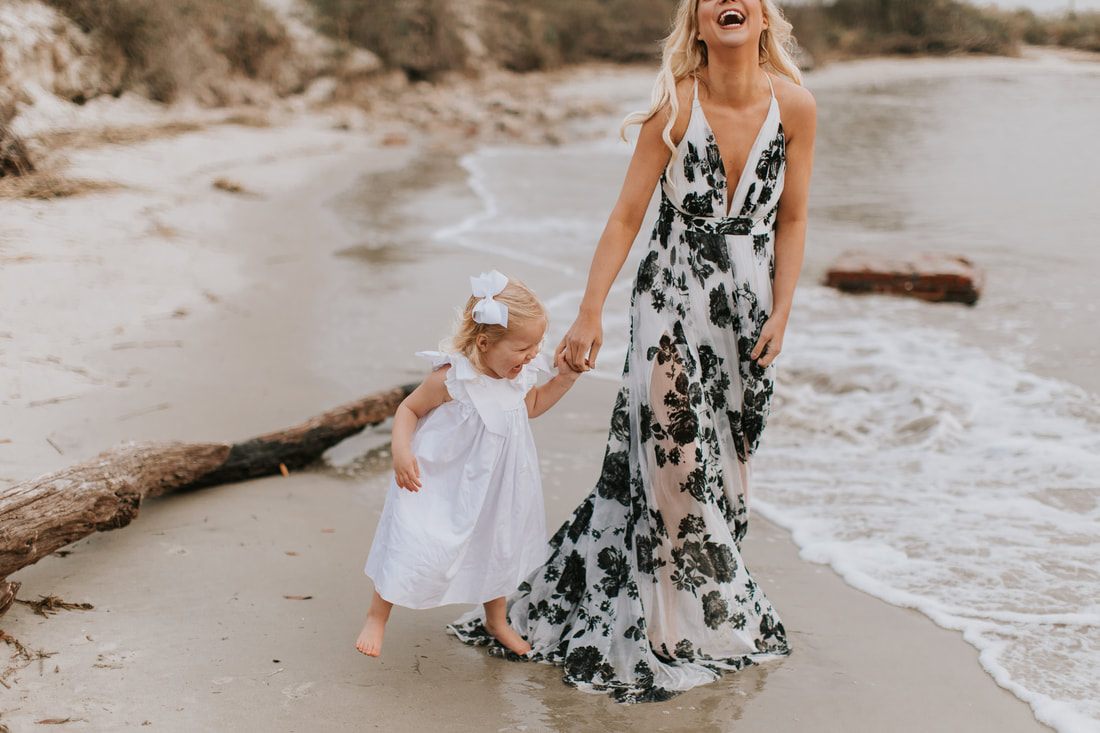 Aubrey reaching up to her mom during their mommy and me beach photos