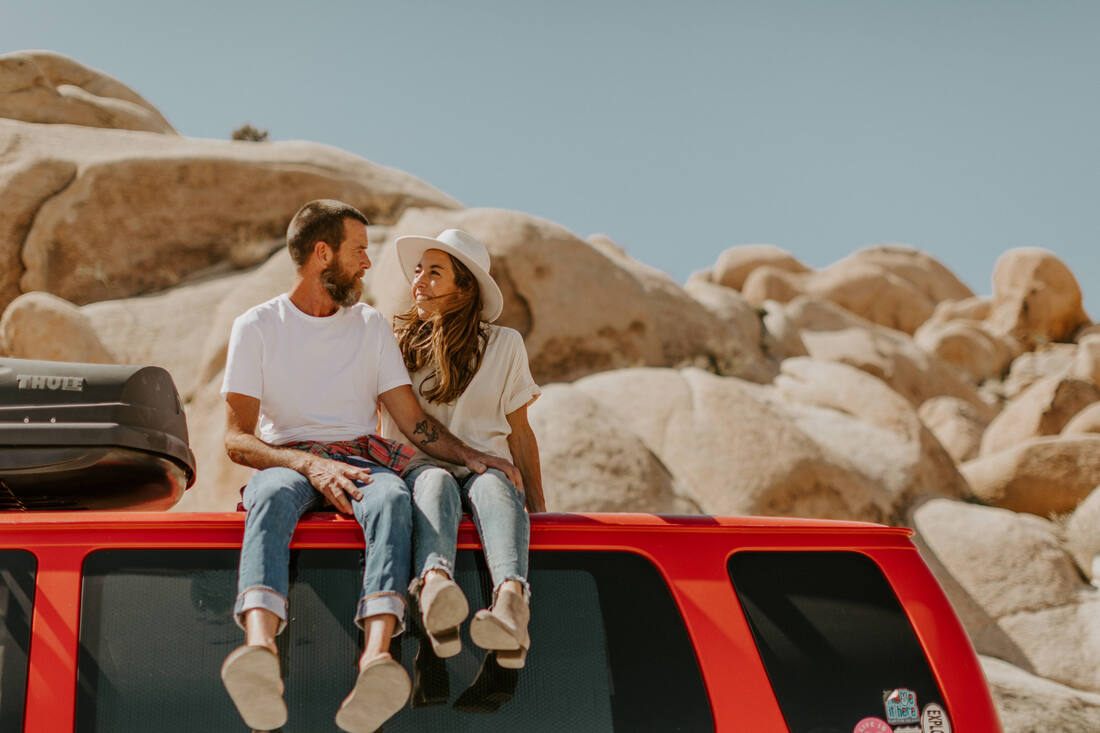 The couple walking hand in hand among Joshua trees at sunset