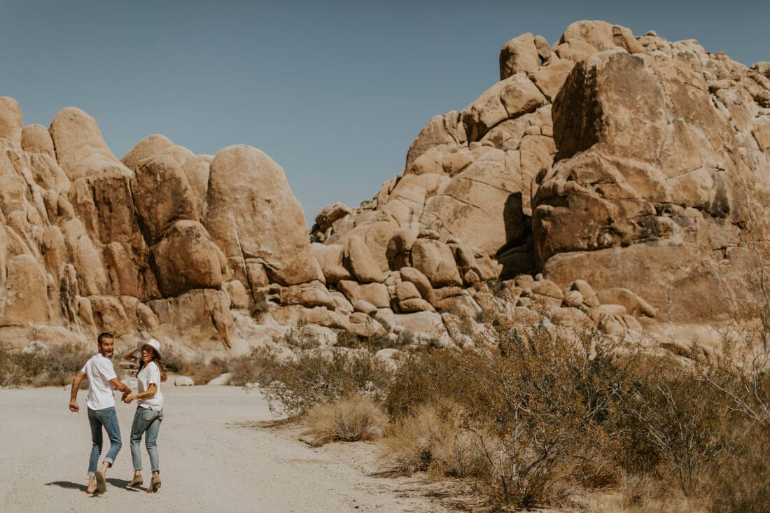 The couple kissing with the iconic Joshua Tree rock formations behind them