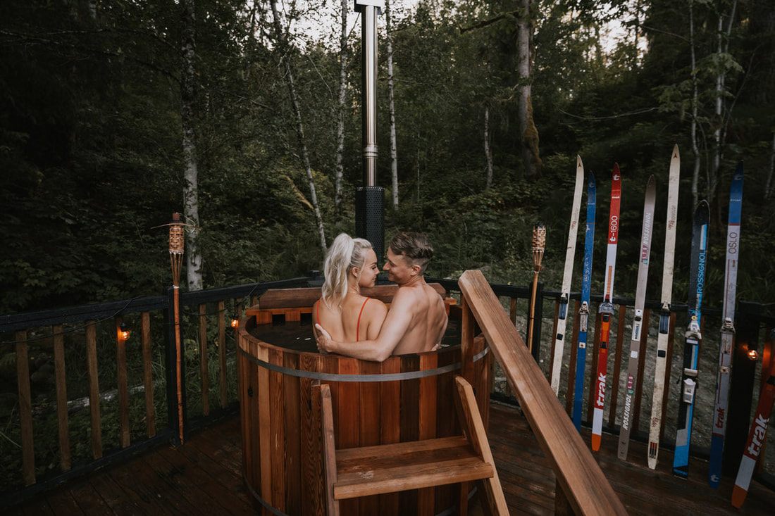 The couple walking hand in hand through the woods near the cabin