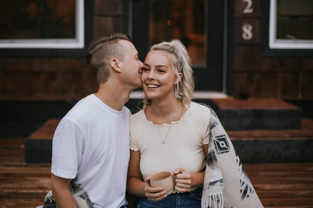 The couple embracing on the porch of the a-frame cabin in Stevens Pass