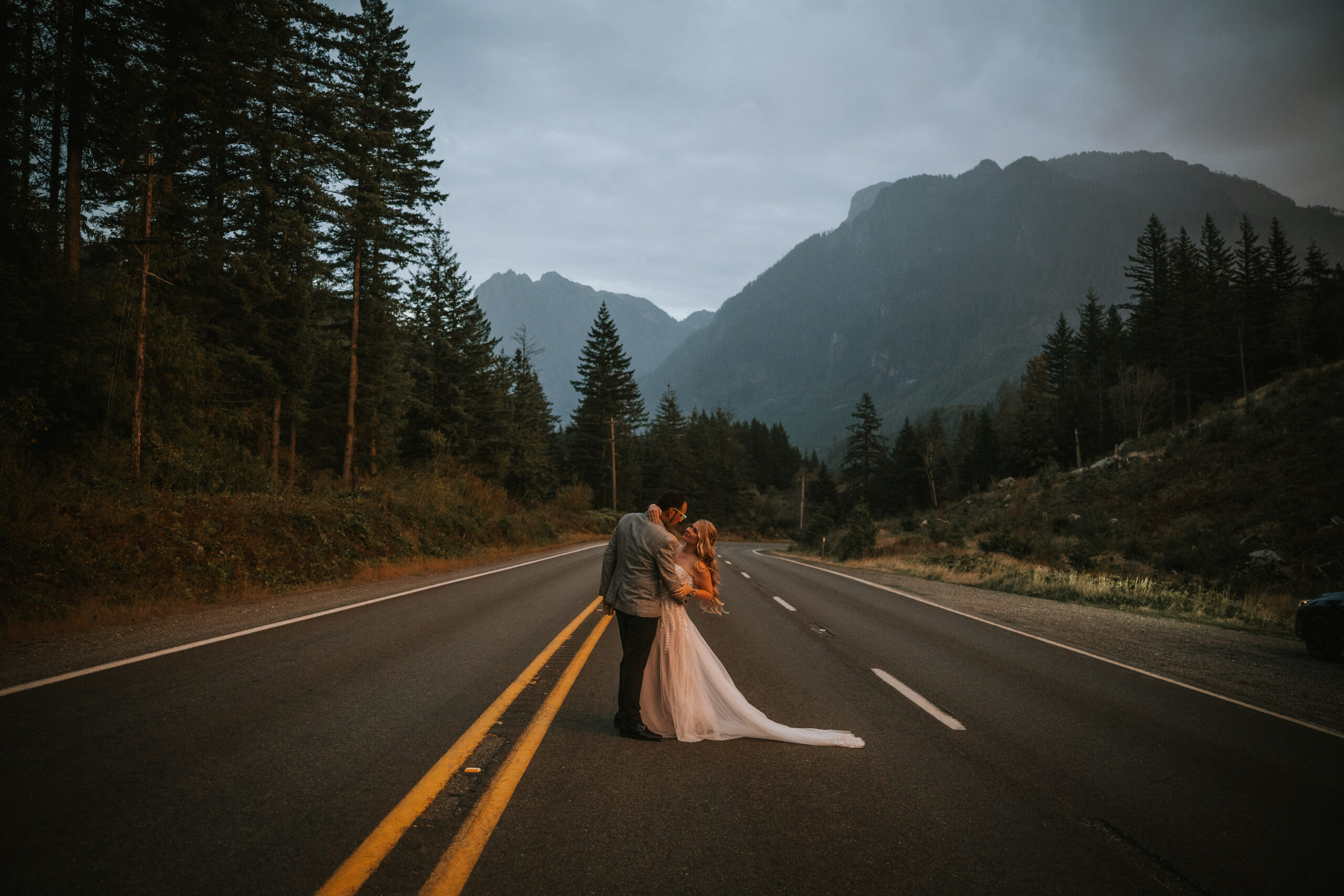 Justine and Zack together on an empty mountain highway with the Cascades ahead