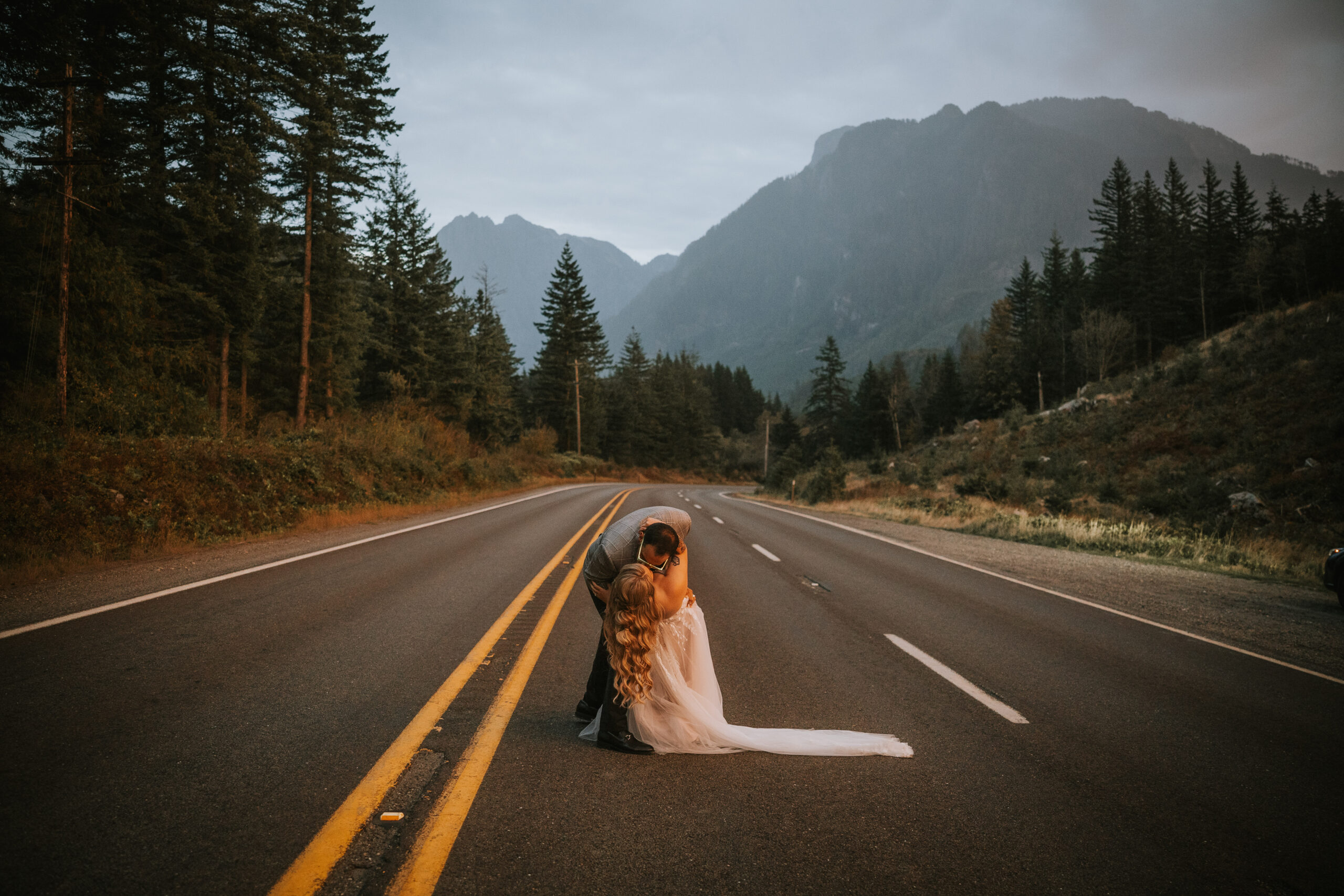 The couple sitting on the center line of the highway, her train spread across the road