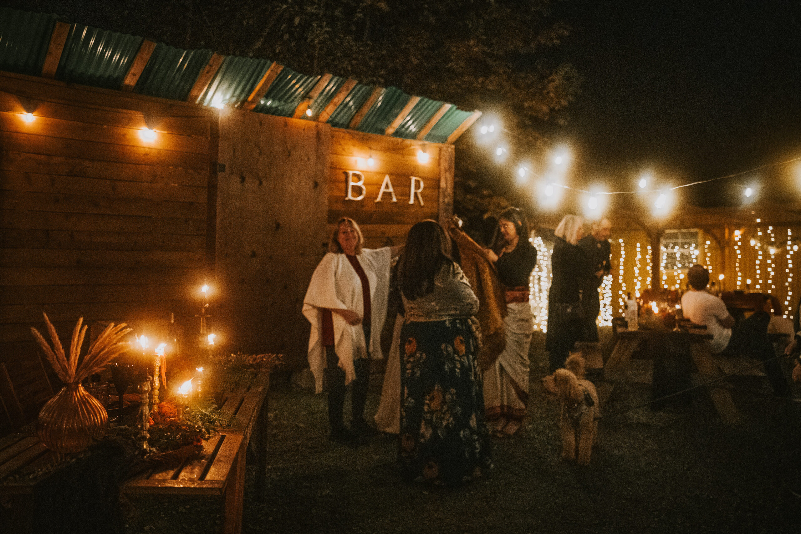 Guests gathered at the outdoor bar under string lights after dark