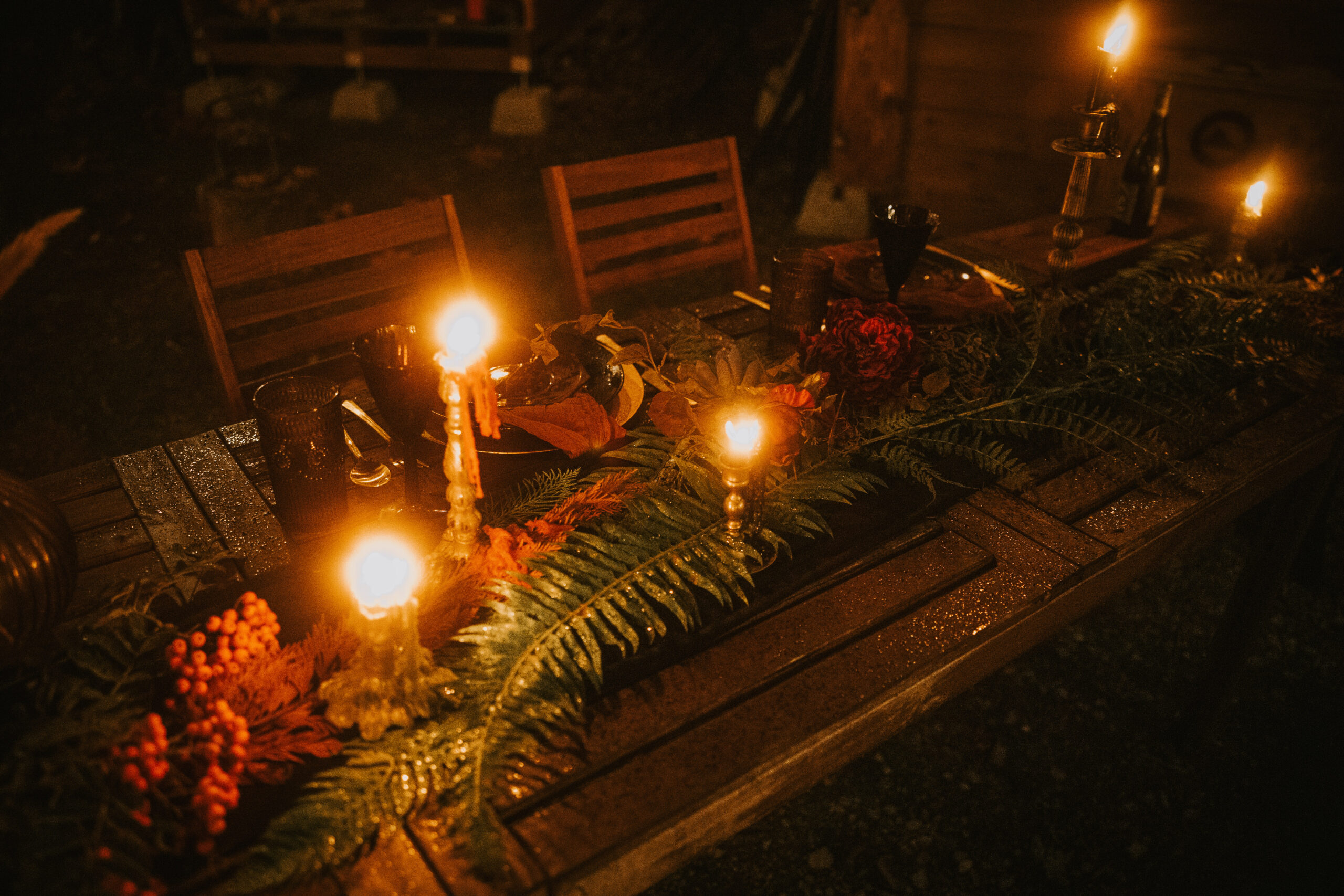 Candlelit table with ferns and rowan berries glowing in the dark
