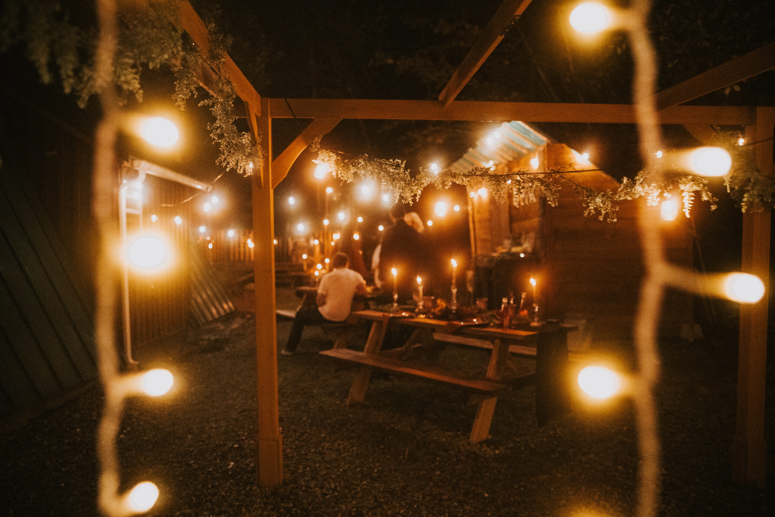 The pergola and picnic tables strung with lights late in the evening