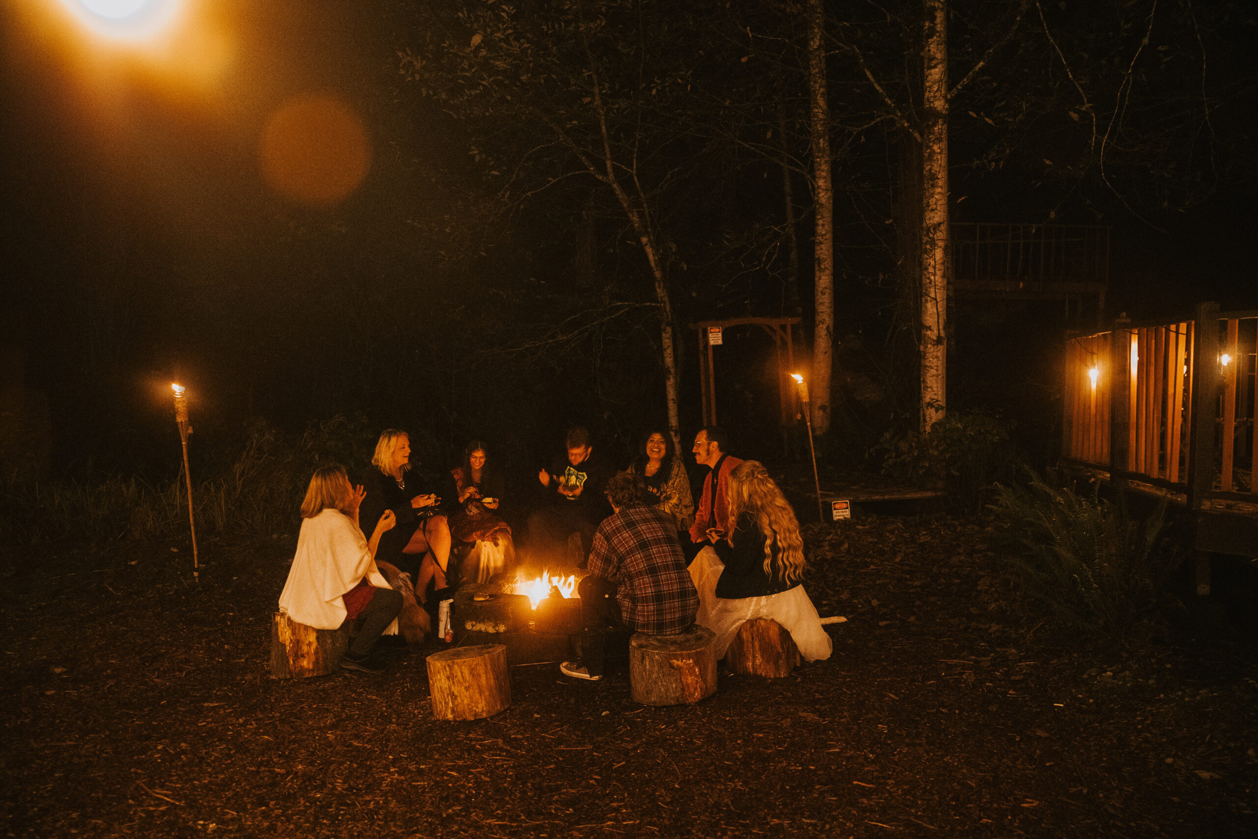 Guests sitting on stumps around the bonfire at the end of the night