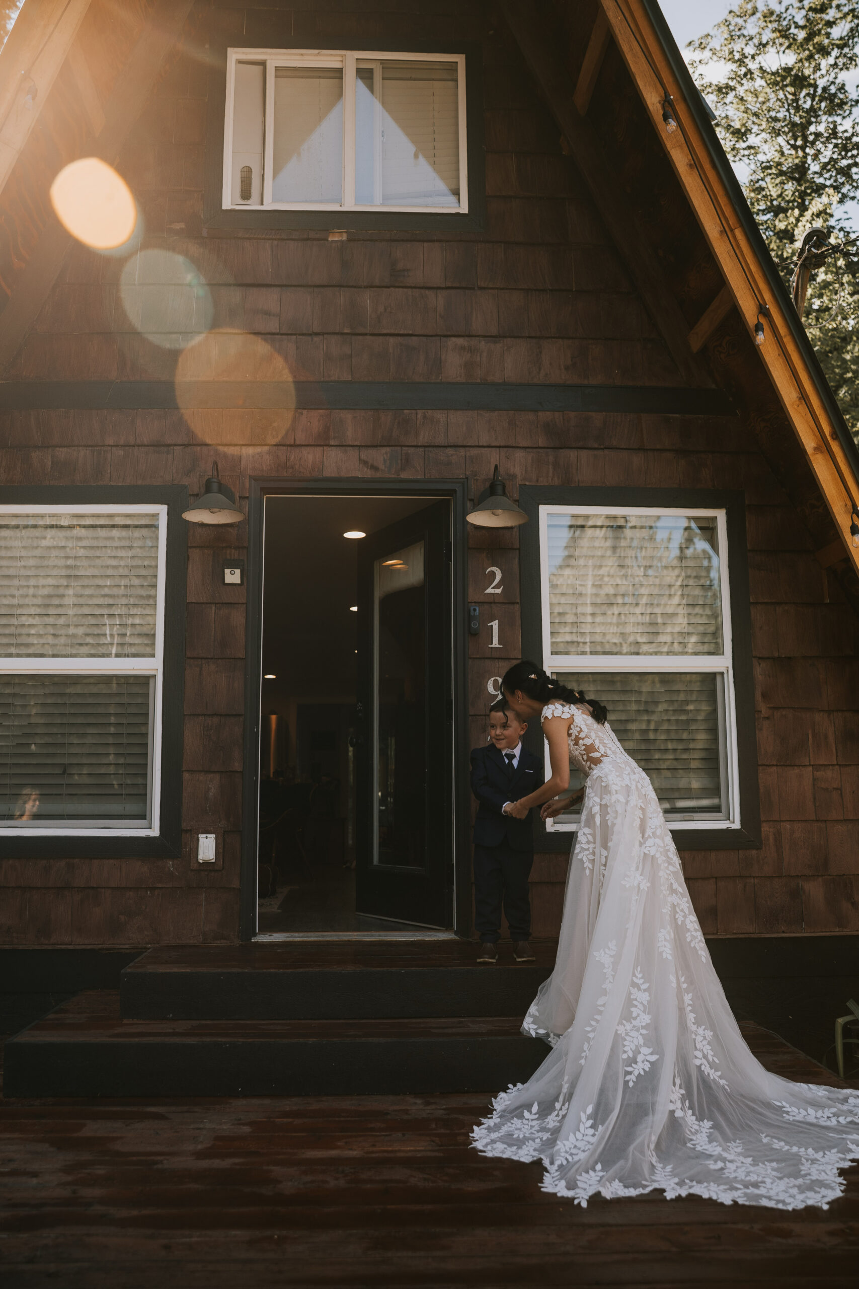 Morgan leaning down to talk with her son in his navy suit on the cabin steps
