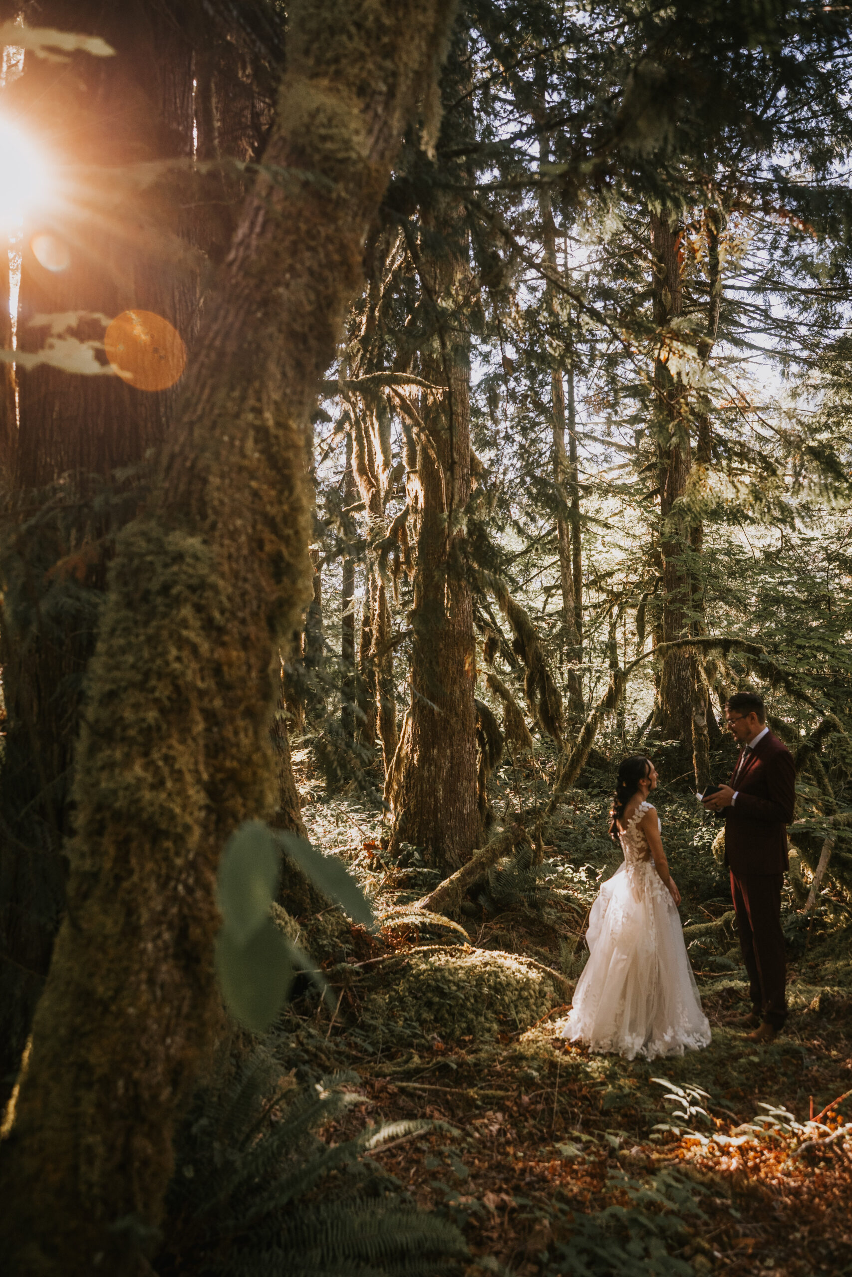 Brandon and Morgan in the mossy forest with late sun coming through the trees