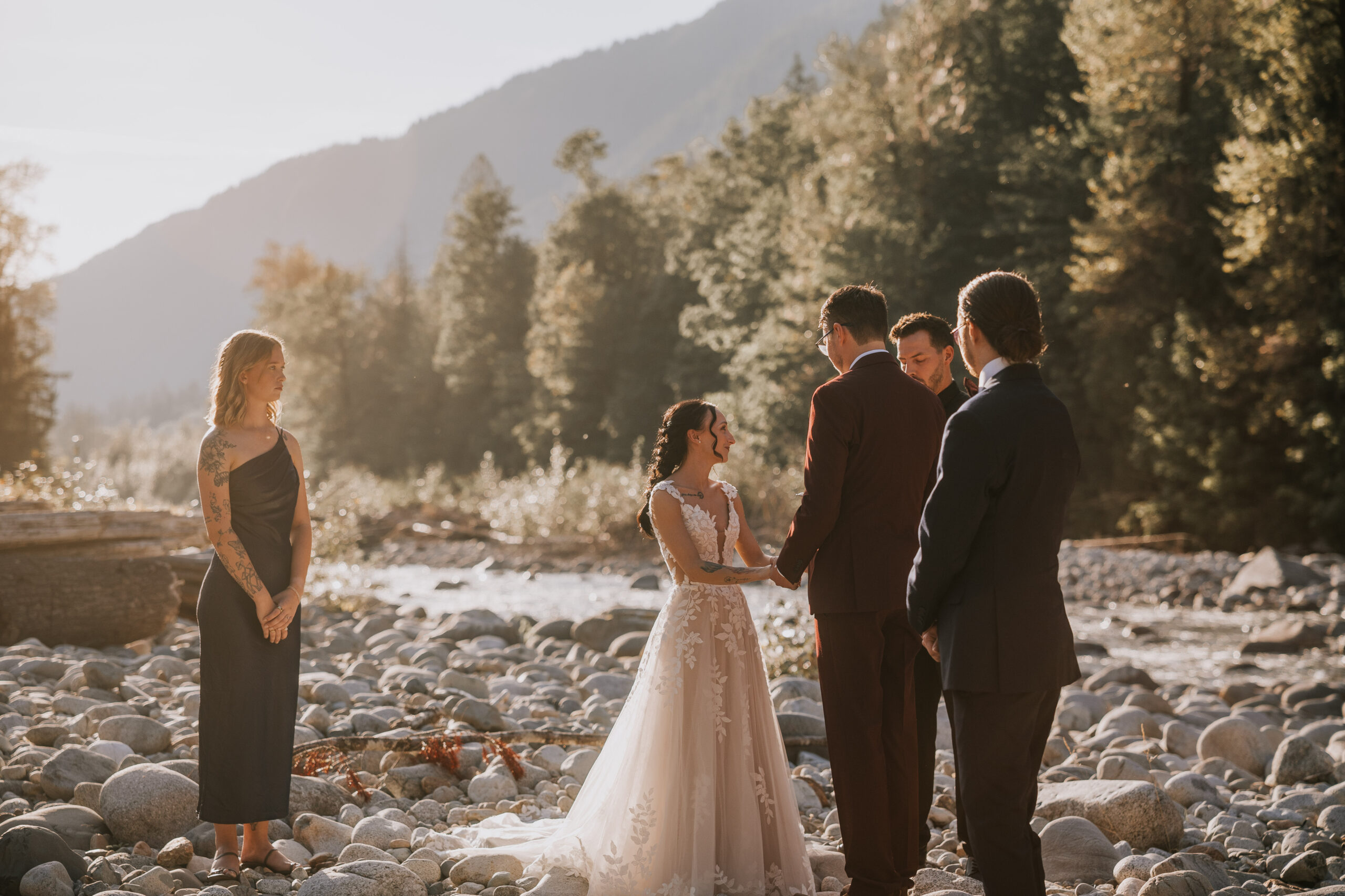 The ceremony on the river rocks with mountains and evergreens behind