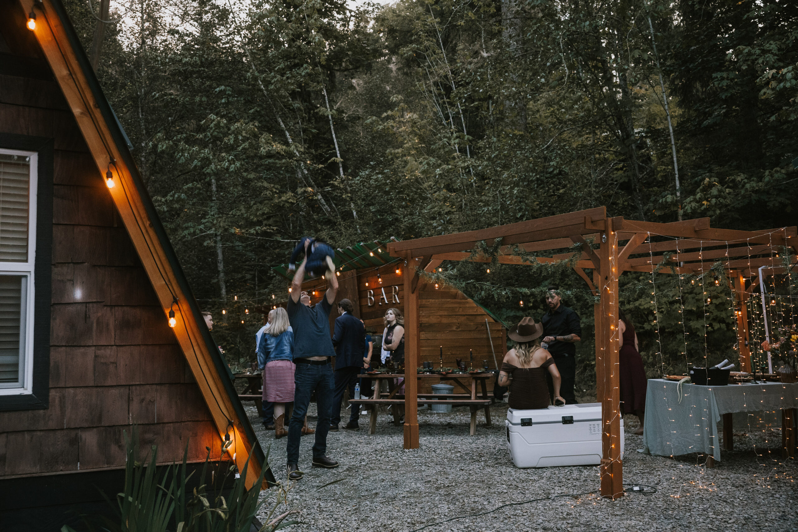 Guests under the pergola beside the A-frame cabin in the evening