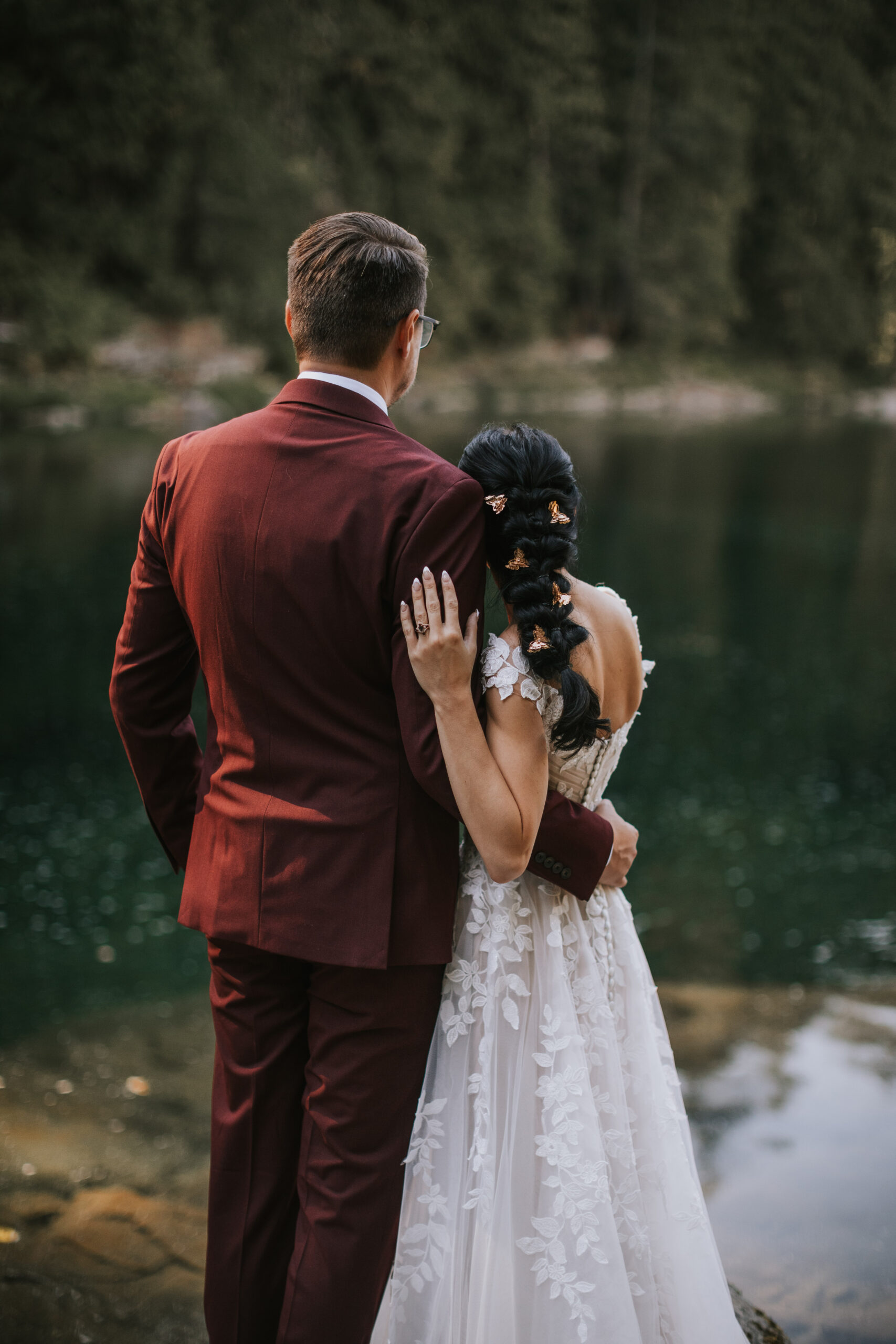 Brandon and Morgan from behind, her hand on his shoulder, looking out over the water