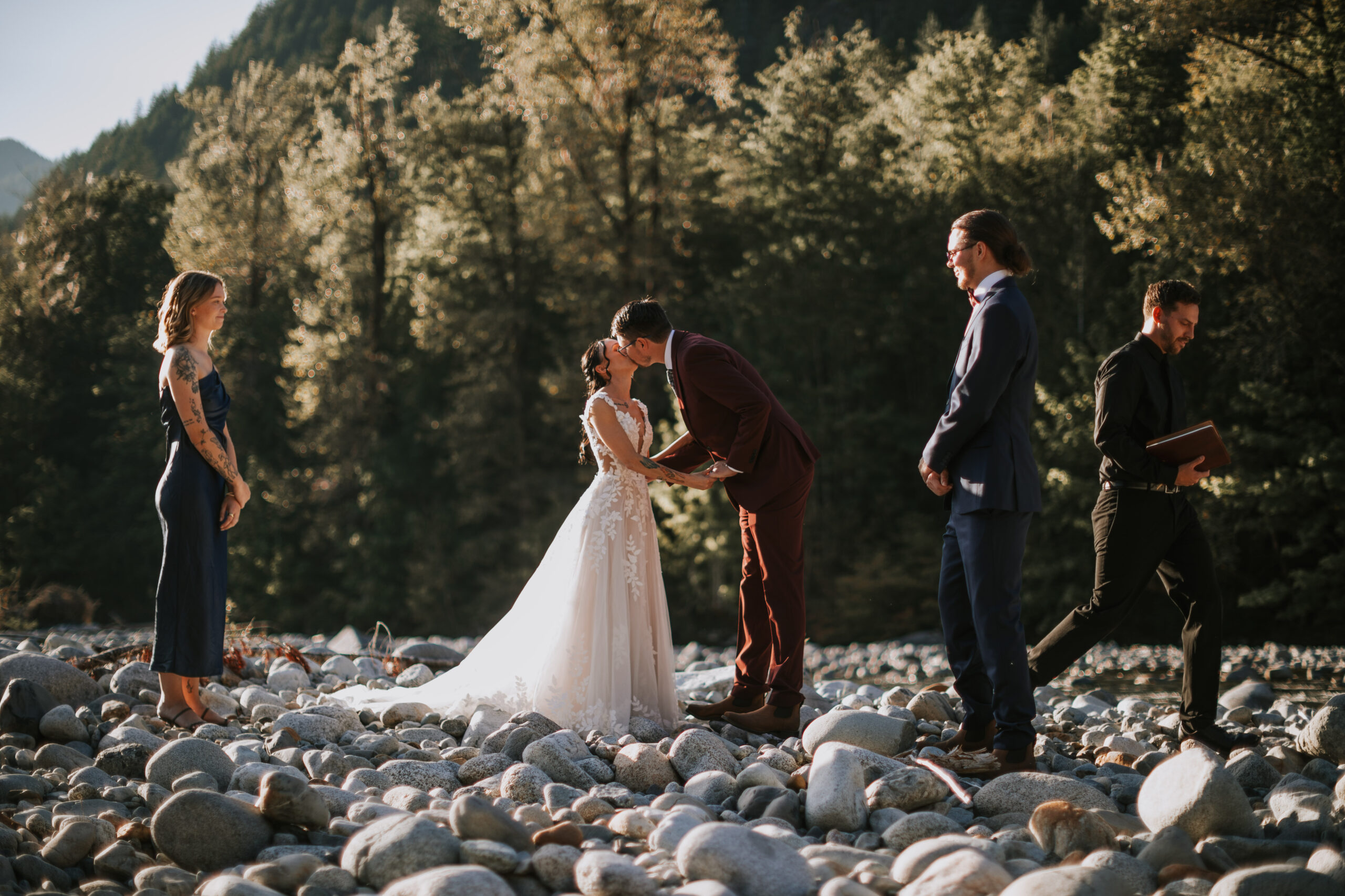 Brandon and Morgan's first kiss on the river rocks with their guests looking on