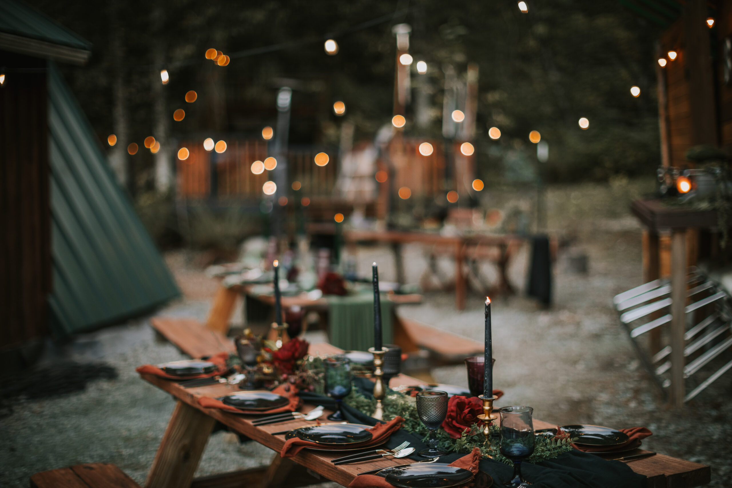 The dinner tables and string lights glowing between the cabin and the trees