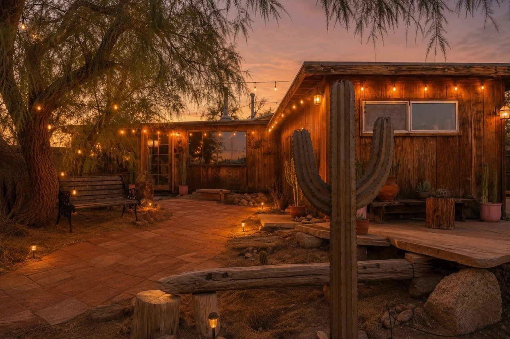 The main house at That Desert Space at dusk, string lights across the patio and a saguaro beside the deck